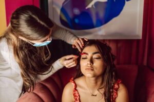 a woman with brown hair getting her makeup done