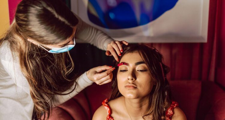a woman with brown hair getting her makeup done