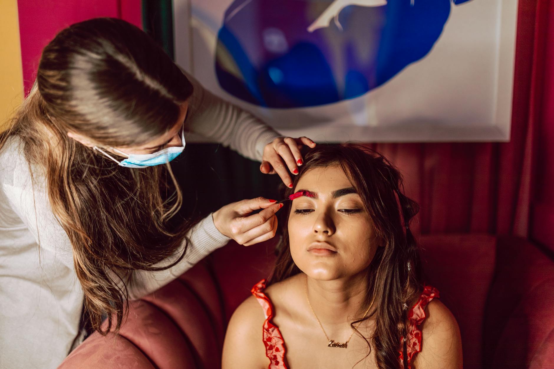a woman with brown hair getting her makeup done
